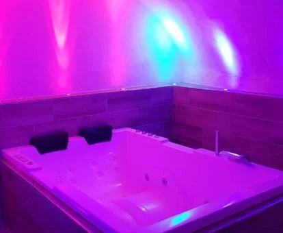 Foto del jacuzzi rectangular para dos personas con luces de color rosa y morado debajo de una techo en forma de bóveda en la casa rural La casita de Fuente Obejuna